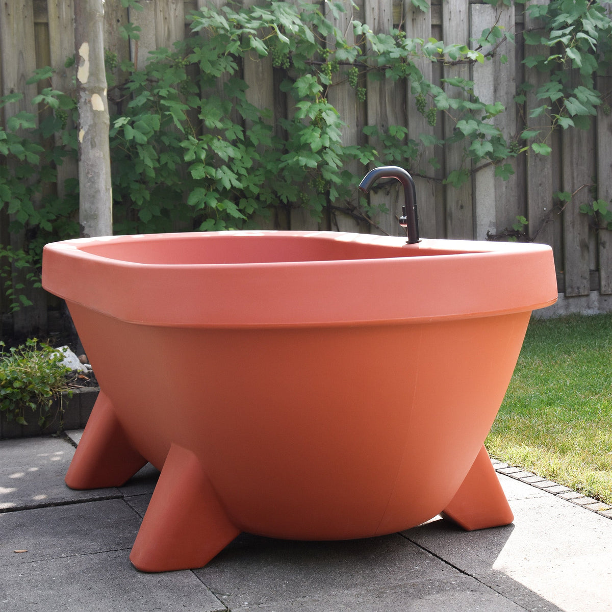 Terracotta Gardentub outdoor bath with black tap on a garden terrace